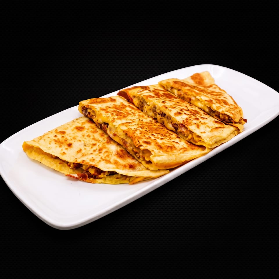 A white rectangular plate holds four golden-brown quesadillas filled with meat and melted cheese.